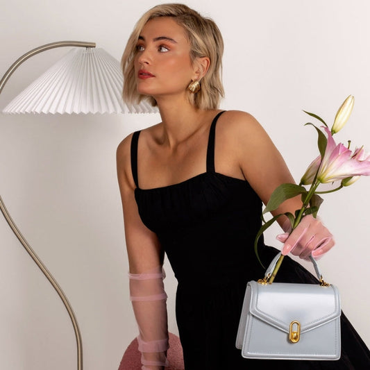 woman holding white leather top handle bag minimalist crossbody style outfit