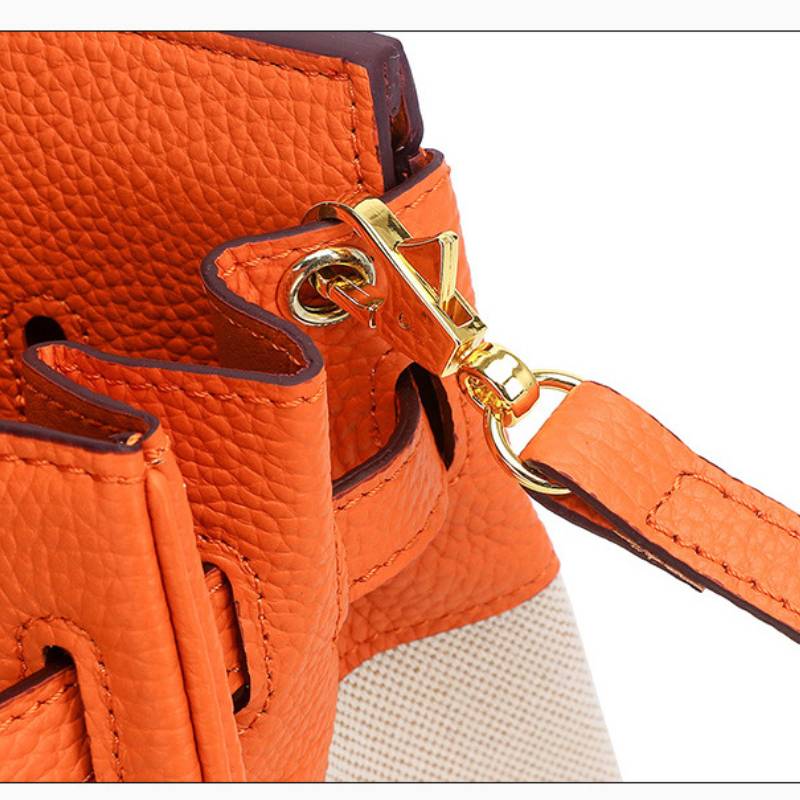 Close-up of of structured leather canvas handbag with a gold clasp on a white background