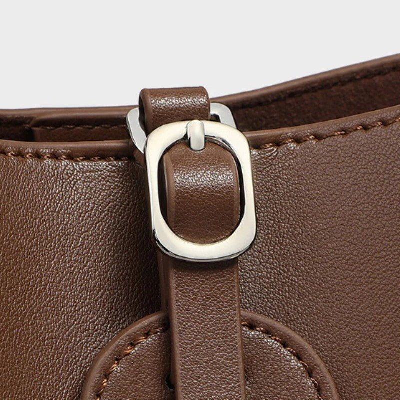 Small leather bucket bag close-up showing buckle hardware detail
