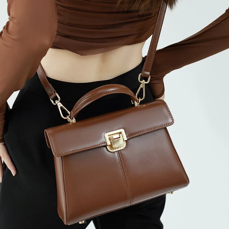 Top Handle Crossbody Genuine Leather Bag with Lock Closure in dark brown color held by model as a crossbody style