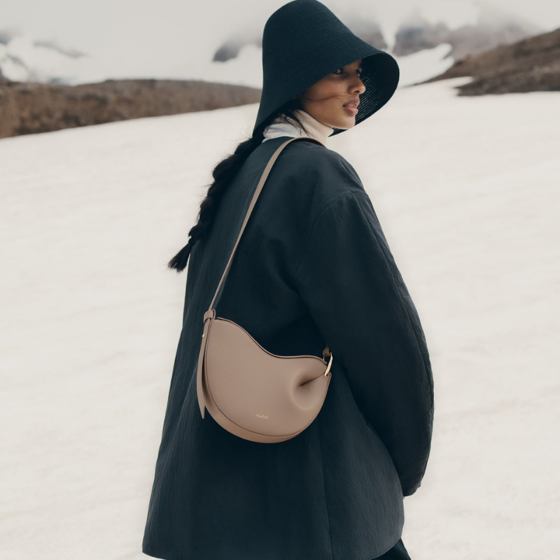 Woman wearing a genuine leather crescent shoulder bag in beige