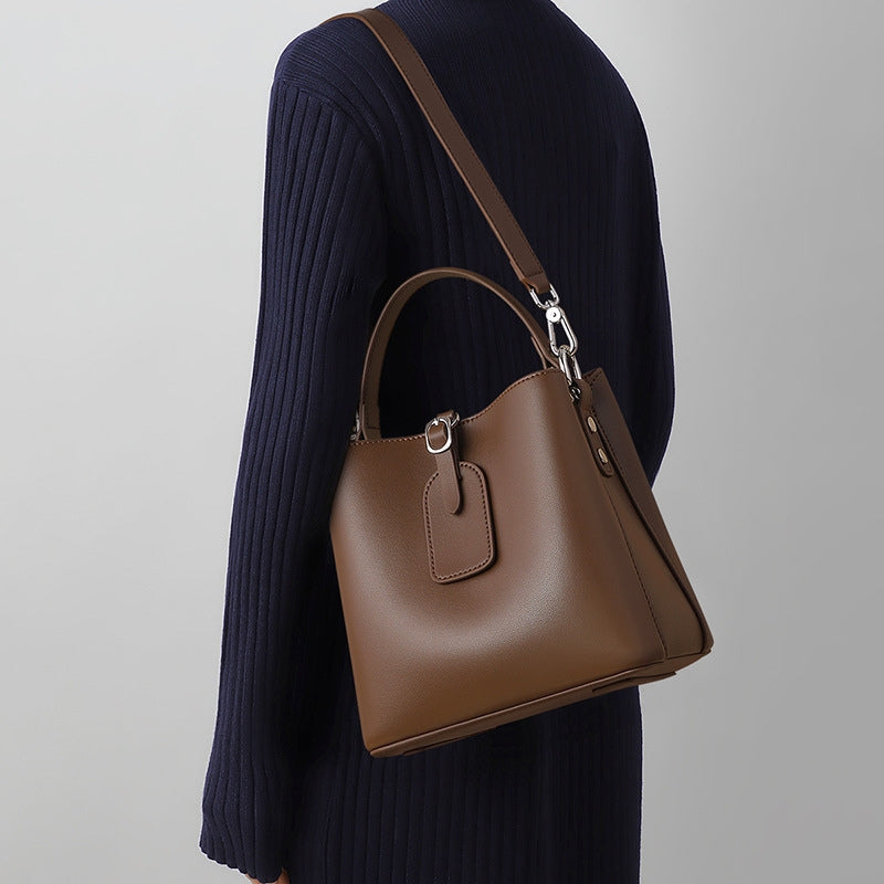 Woman wearing small leather bucket bag, brown, crossbody strap