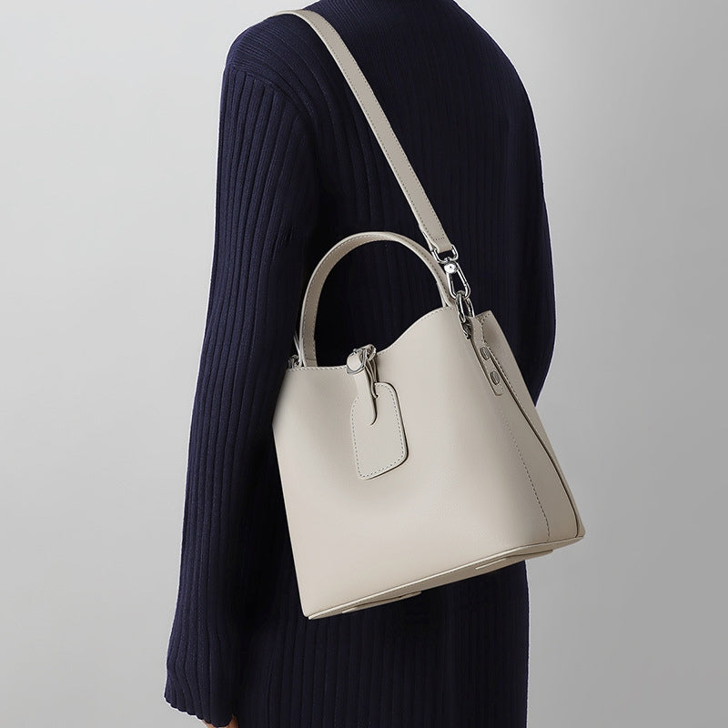 Woman wearing small leather bucket bag in chalk white