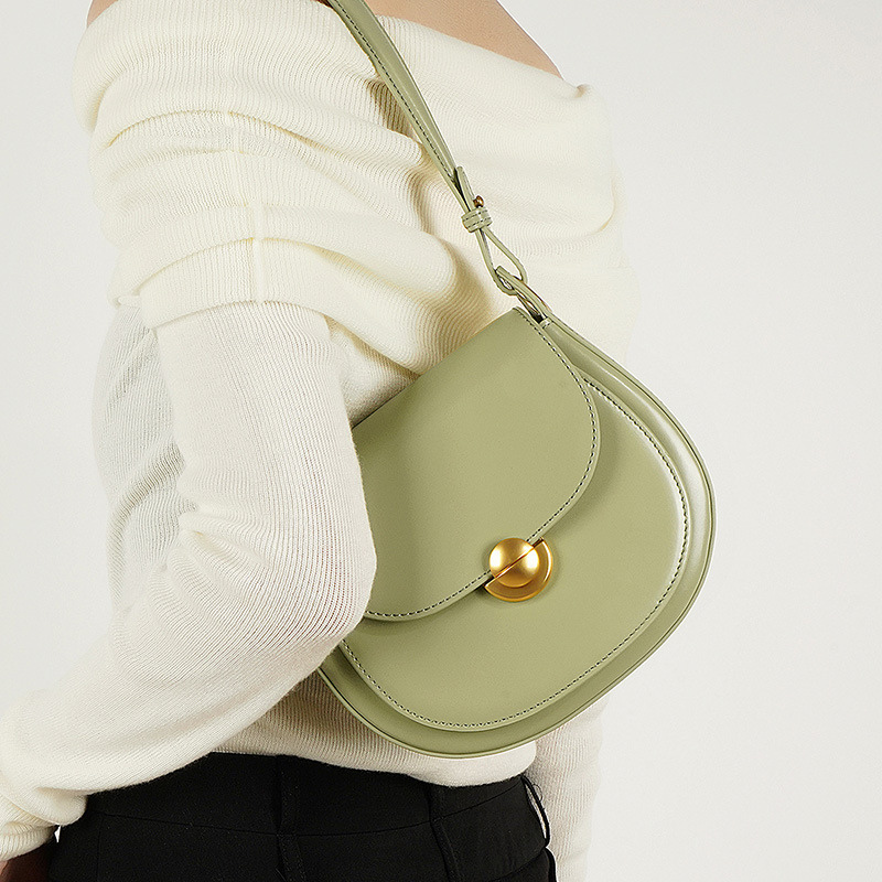 Women’s Minimalist Genuine Leather Lock Buckle Crossbody Saddle Bag in light green color lifestyle model wearing it as a shoulder bag