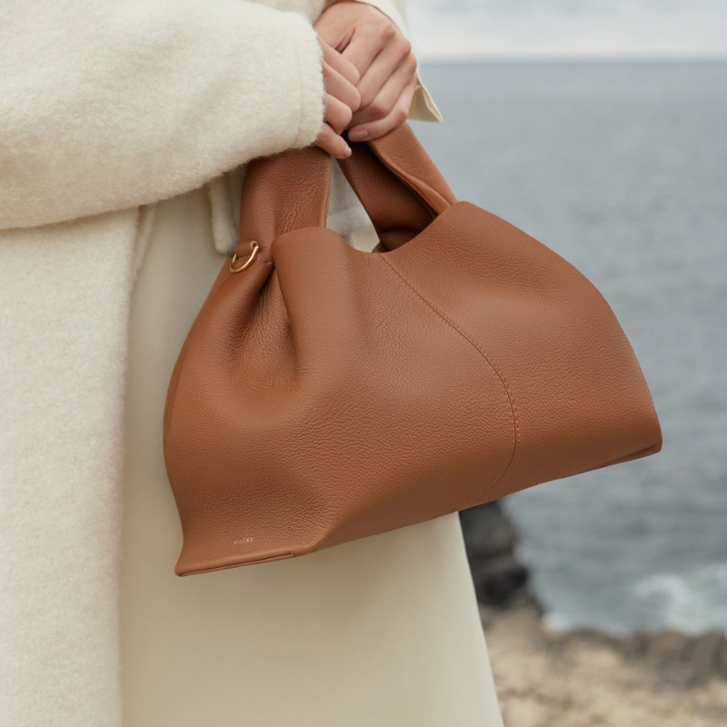 woman carrying top handle shoulder bag in brown leather everyday style